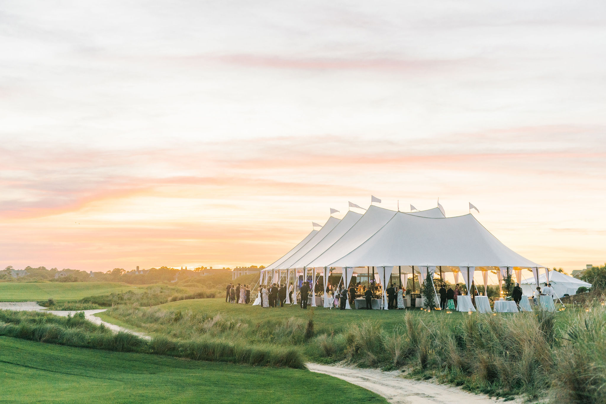 Sailcloth tent reception glowing at sunset over the marsh