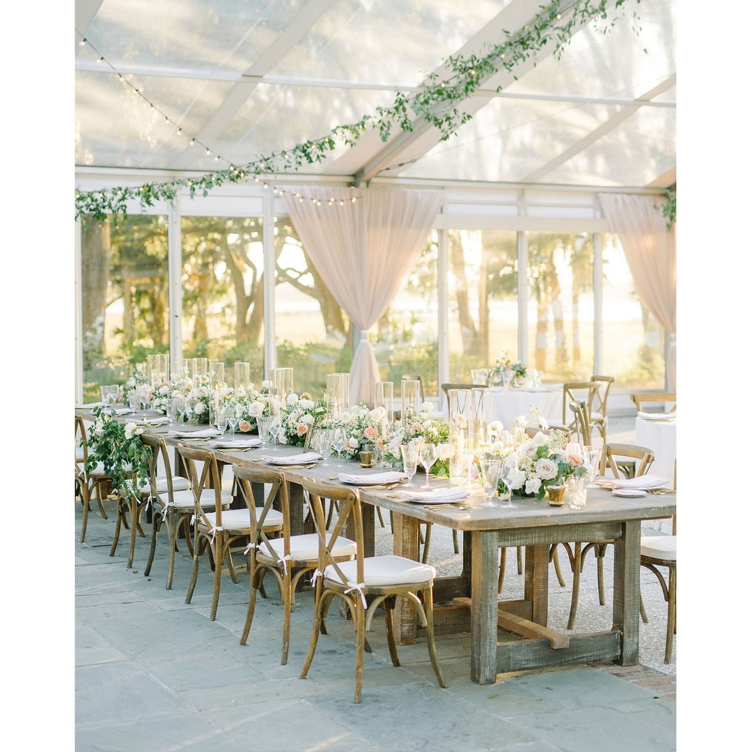 Elegant tented reception under oaks strung with warm lights