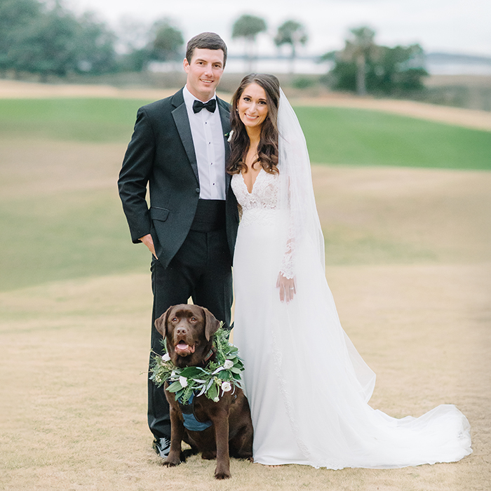 Couple portrait with their retriever on a marsh-front lawn